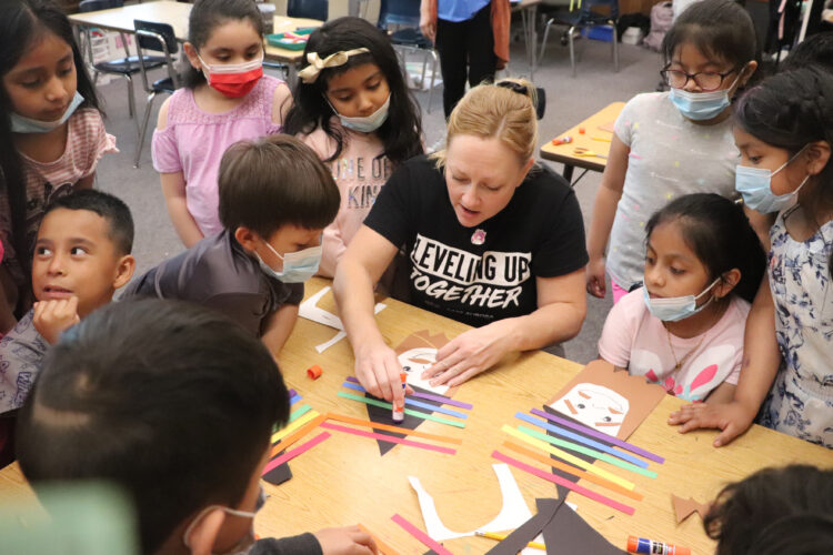 Ms. Johnston shows 1st graders how to make a rainbow wizard. 